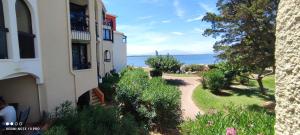 a building with a walkway next to the water at Terrasse vue Etang, piscine Séjour détente in Le Barcarès