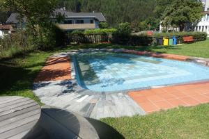 a swimming pool in a yard with an umbrella at Residence Zum Theater in Colle Isarco