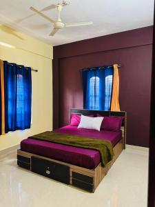 a bedroom with a purple bed with blue curtains at Rivera Holidays in Vythiri