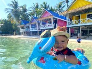 a baby wearing a hat on a raft in the water at Paradiso Ocean front Bungalows in Koh Rong Island