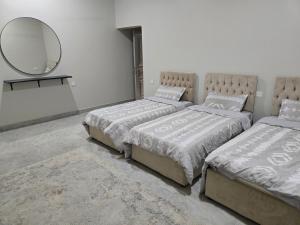 a bedroom with two beds and a mirror and a rug at Katara Garden in As Suwayq +15 photos