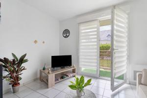 a white living room with a television and a window at Le Cocon De Laurence in Pleurtuit