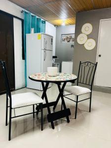 a table and two chairs and a refrigerator at Suite Antiguo in Antiguo Cuscatlán