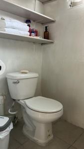 a bathroom with a toilet and towels on shelves at Suite Antiguo in Antiguo Cuscatlán