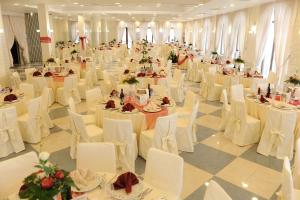 um salão de banquetes com mesas brancas e cadeiras brancas em Hotel Dell'Arpa em Viggiano
