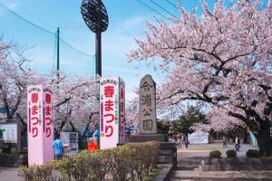 a park withakura trees and signs in front of a monument at AOMORI LOVERS Minatomachi Base in Aomori