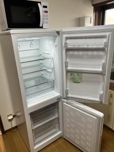 an empty refrigerator with its door open in a kitchen at AOMORI LOVERS Minatomachi Base in Aomori