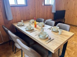 a wooden table with chairs and plates and utensils at AOMORI LOVERS Minatomachi Base in Aomori