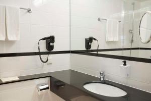 a bathroom with a sink and a phone on the wall at Scandic Wrocław in Wrocław