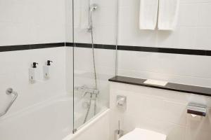 a white bathroom with a shower and a toilet at Scandic Wrocław in Wrocław