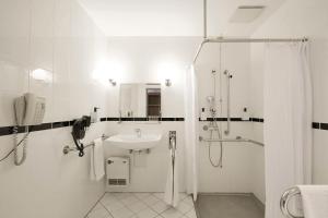 a white bathroom with a sink and a shower at Scandic Wrocław in Wrocław