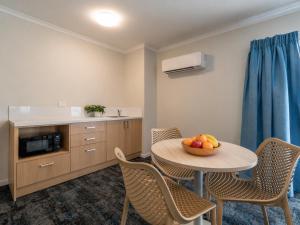 a room with a table and chairs with a bowl of fruit at Cairns Southgate Hotel in Cairns