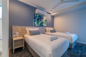 a hotel room with two beds and a table at Cairns Southgate Hotel in Cairns