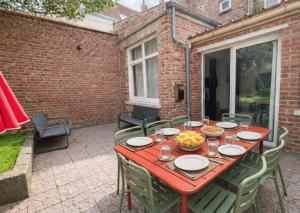 a red table with chairs on a patio at Le Repaire des 12- Hypercentre, jardin, idéal groupe, 5 chambres 5 salles de bain in Saint-Omer