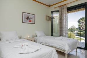 a bedroom with two beds with white sheets and a window at Zeusplace Crown Platamon in Platamonas