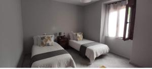 a white room with two beds and a window at Estación celorio in Celorio