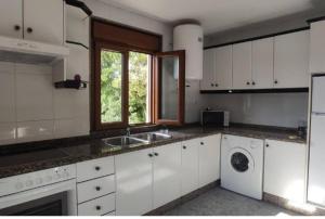 a kitchen with white cabinets and a sink and a window at Estación celorio in Celorio