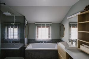 a bathroom with a large tub and two windows at La Maison des Champs in Ciney