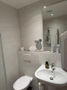 a white bathroom with a toilet and a sink at HELENA Hotel & Restaurant in Mirow