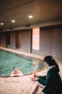 a woman sitting in a swimming pool with a man at Bella Posta Hotel in Soprabolzano