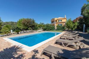 a swimming pool with lounge chairs and a house at Monte das Palmeiras by Algarve Holidays in Loulé