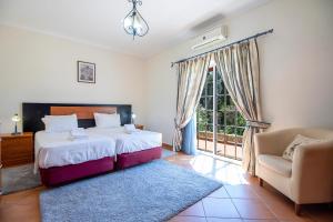 a bedroom with a bed and a chair and a window at Monte das Palmeiras by Algarve Holidays in Loulé +26 photos
