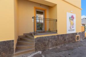 a yellow building with stairs and a balcony at La Pulvarera in Castelsardo