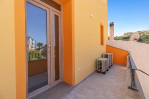 a balcony with an orange wall and a sliding glass door at La Pulvarera in Castelsardo