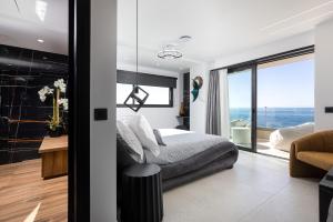a bedroom with a bed and a view of the ocean at Moonlight Villas Calypso - Sleek Coastal Living by etouri in Koutsourás