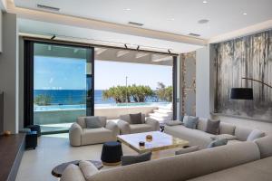 a living room with two couches and a large window at Moonlight Villas Calypso - Sleek Coastal Living by etouri in Koutsourás