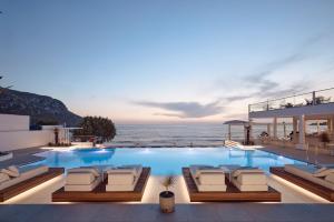 a pool with chairs and the ocean in the background at Kantouni Beach Boutique Hotel in Panormos Kalymnos