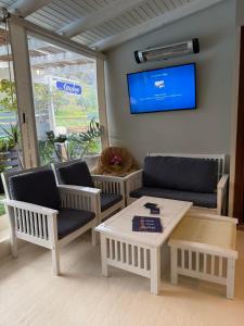 a living room with chairs and a table and a tv at Attalos Apartments in Agia Pelagia