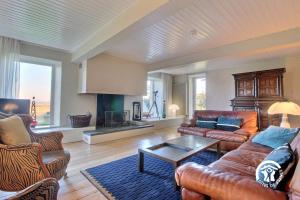 a living room with leather couches and a table at Fenêtres sur le golfe in Sarzeau