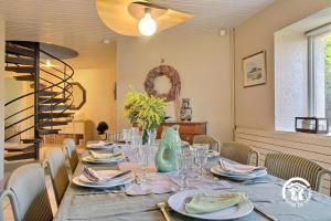 a dining room with a table with plates and glasses at Fenêtres sur le golfe in Sarzeau