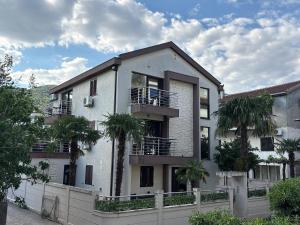 a white building with palm trees in front of it at Apartments Villa Stefan in Budva