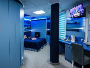 a blue room with a bed and a desk and a television at Sobe i Apartmani Vila Modex in Paraćin