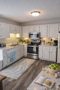 a kitchen with white cabinets and appliances and a table at Tranquil Retreat - Close to everything you need in Osage Beach +13 photos