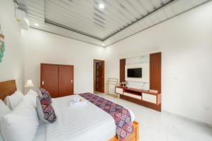 a bedroom with a white bed and a television at Anta Villa Lembongan in Nusa Lembongan
