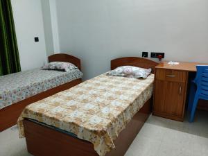 a room with two beds and a desk and a table and a deskictericter at The Palindrome in Guwahati