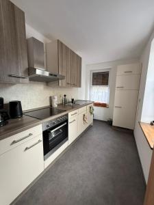 a kitchen with white cabinets and a stove top oven at Ferienwohnung Waidmannsheil in Amtsberg
