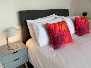 a bed with red and white pillows and a night stand at Consett Gorgeous Two Bedroom Apartment in Consett