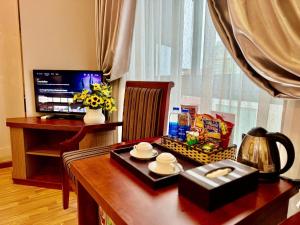 a desk with a computer monitor and a table with food at Gllant Villa Hà Nội in Hanoi