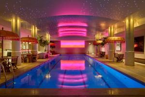 a large swimming pool with purple lights in a building at Haymarket Hotel, Firmdale Hotels in London