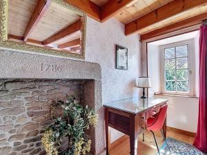 a room with a desk and a stone fireplace at La petite maison du cap in Omonville-la-Rogue +22 photos