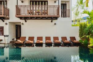 a hotel pool with chairs and a balcony at El Barrio Lanna in Chiang Mai
