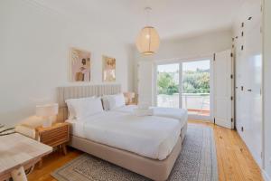 a white bedroom with a bed and a large window at Villa Vintage, By Home Match in Azeitao +73 photos