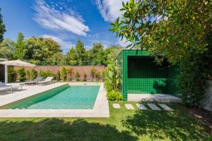 a swimming pool in a backyard with a green wall at Villa Vintage, By Home Match in Azeitao