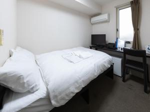 a hotel room with a white bed and a desk at Tabist Ishinomaki in Ishinomaki