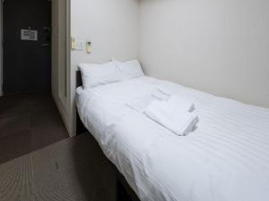 a large white bed with two white towels on it at Tabist Ishinomaki in Ishinomaki