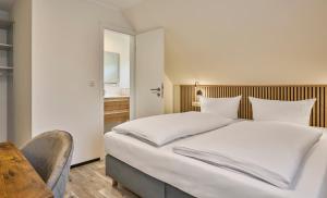 a bedroom with a large white bed and a table at Gästehaus am Weinberg in Oberheimbach +3 photos